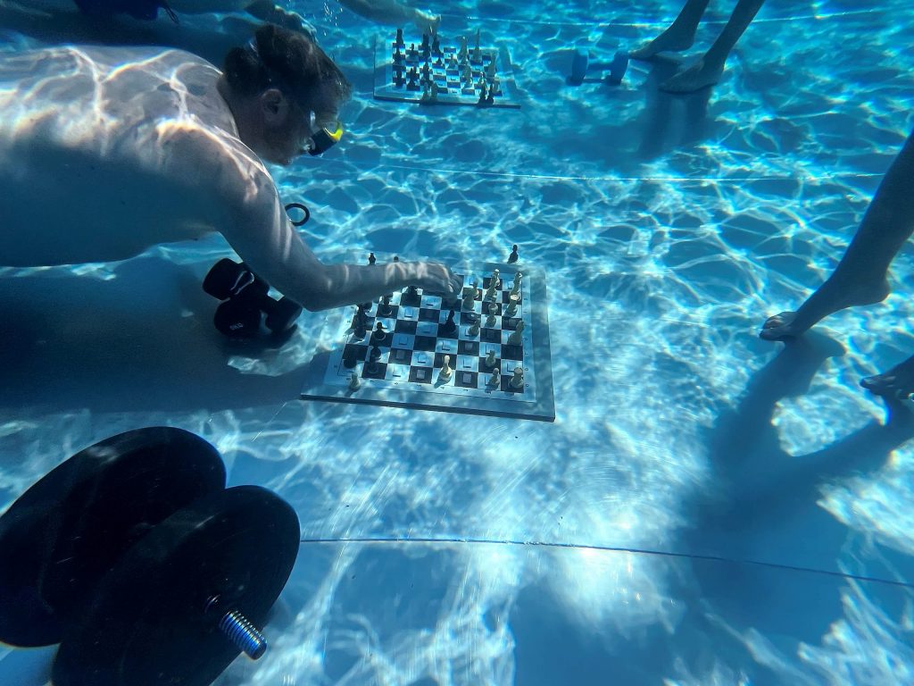 Unterwasserschach: Ein Mann mit setzt beim Tauchen eine Figur auf einem Schachbrett